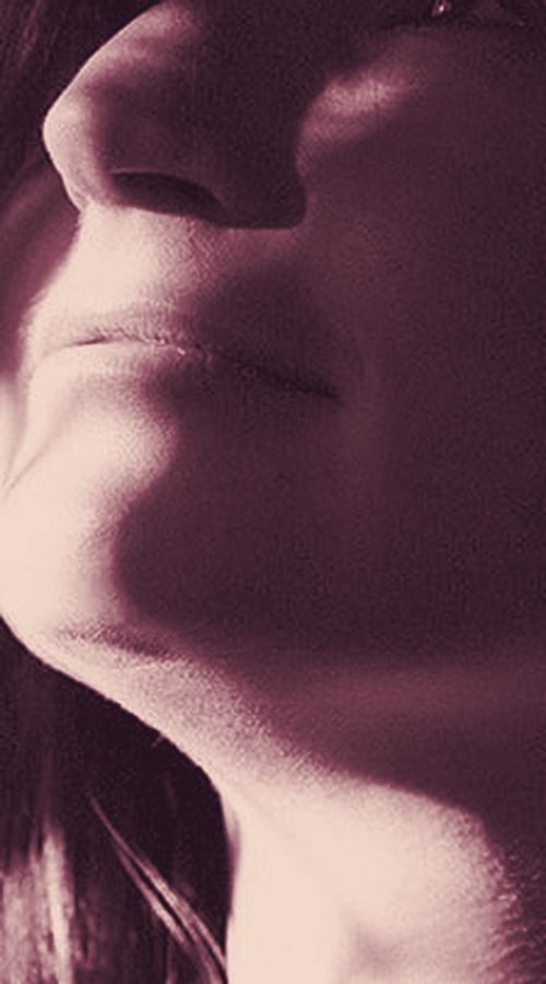 Close-up of lips, jaw and throat tilted up into the light