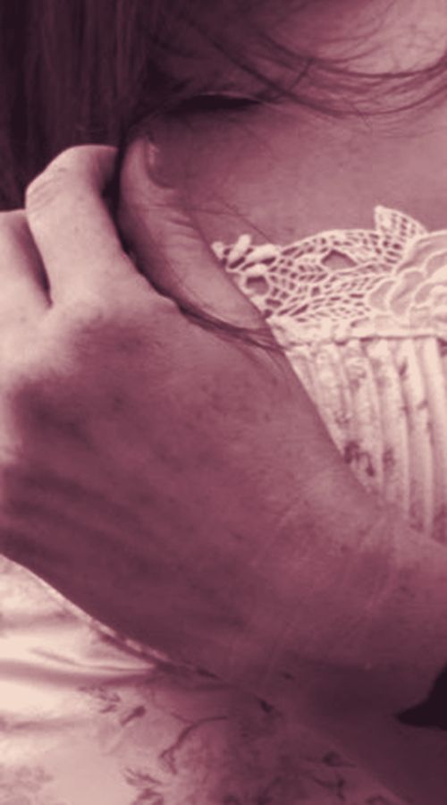 Close-up of a hand resting on bare skin at the collarbone