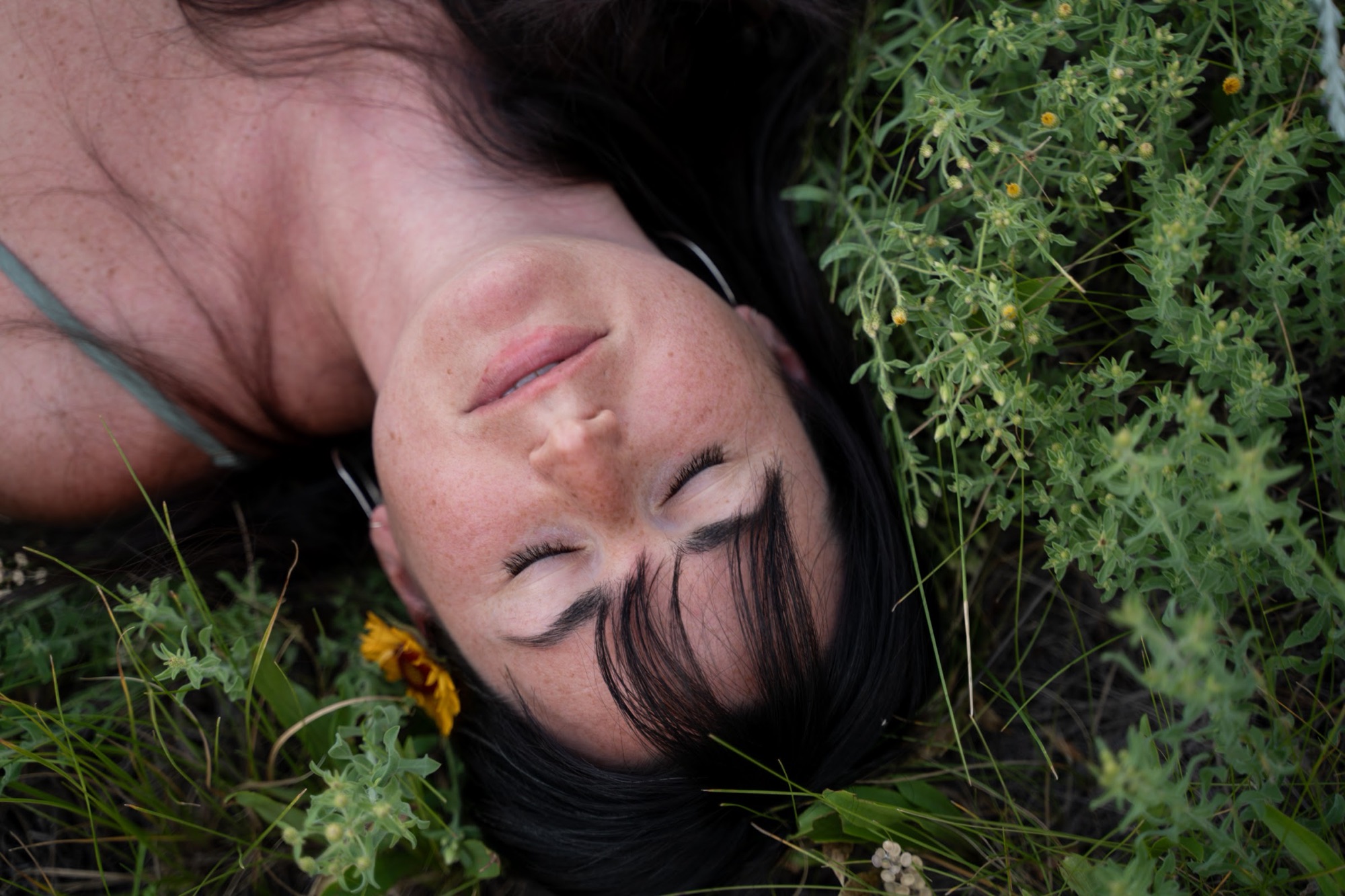 Jade Levinson lying in green grass, eyes closed, face tipped toward the sun