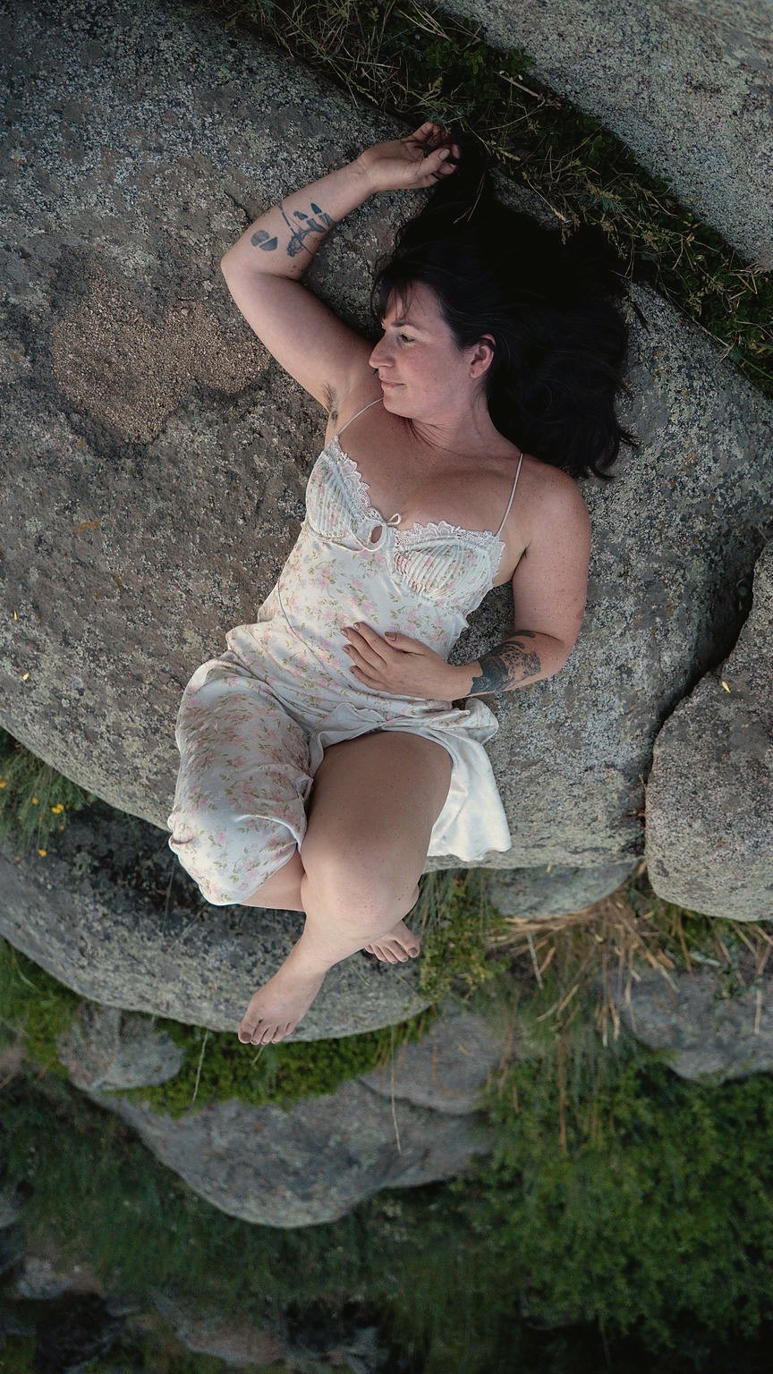 Jade Levinson resting on a granite boulder in a floral slip