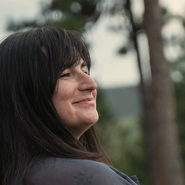 Jade Levinson smiling with her eyes closed among pine trees
